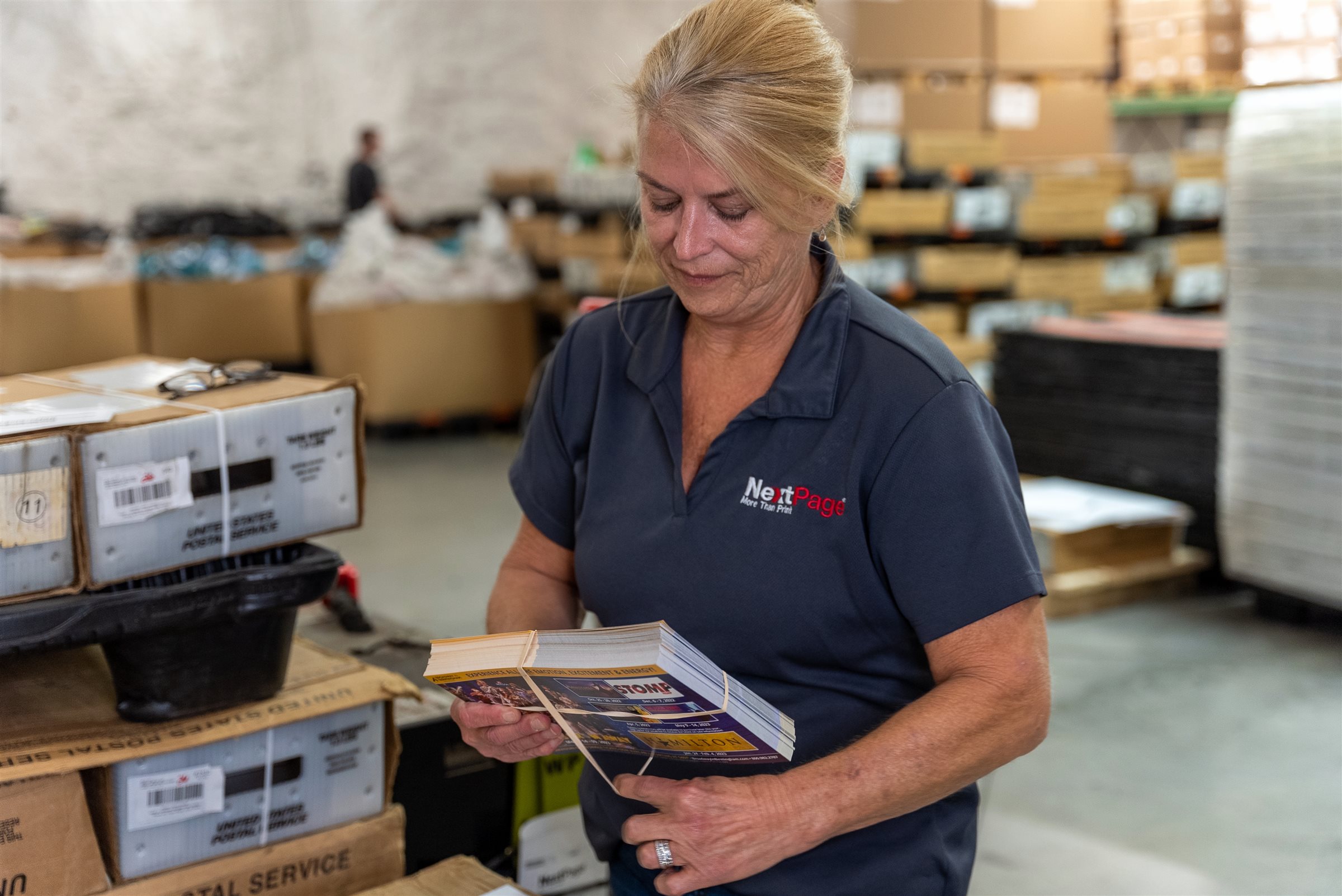 NextPage team member checking a bundle of printed postcards in the mailing area